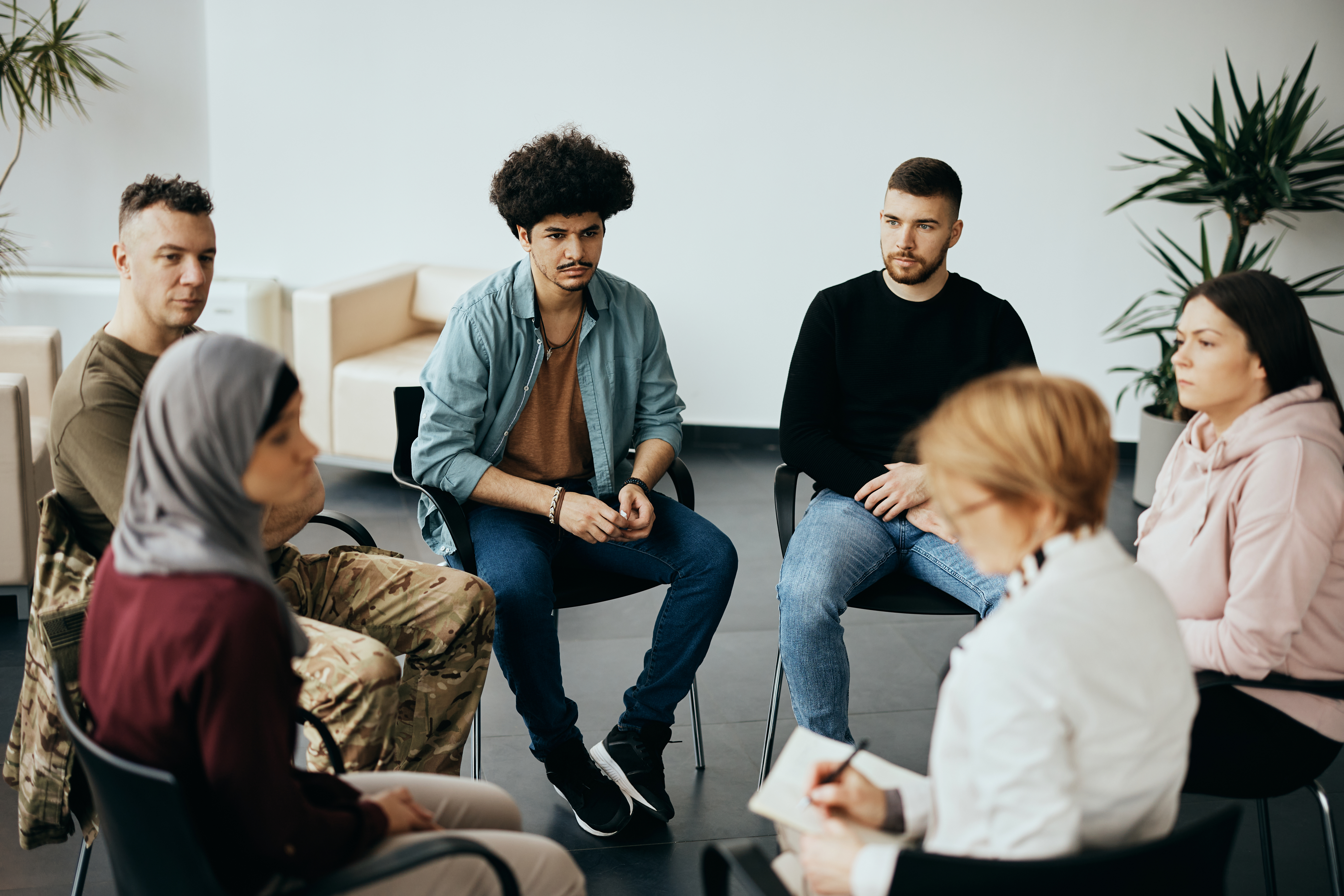 Multi-ethnic participants on group therapy having meeting with their psychotherapist at community center.